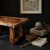 Corner detail of live edge coffee table with a carved rosette inlay beside wood, brass and linen samples
