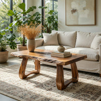 Live edge coffee table with a carved rosette inlay in a sunlit room with large windows and plants