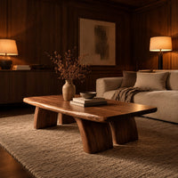 Live edge coffee table with a thick slab top and four stout tapered legs in an evening living room with walnut wall paneling