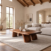 Live edge coffee table with a thick slab top and four stout tapered legs in a bright open plan living room