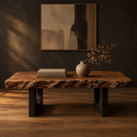 Live edge coffee table on two slab legs with arched cutouts in a dark studio against a charcoal plaster wall
