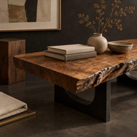 Corner detail of live edge coffee table on two slab legs with arched cutouts beside wood, brass and linen samples