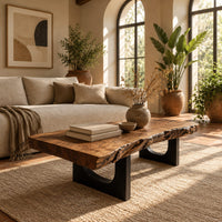 Live edge coffee table on two slab legs with arched cutouts in a bright living room with arched windows and plants