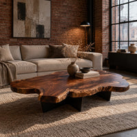 Live edge coffee table with a freeform slab top and dark angular base in an industrial loft living room with exposed brick