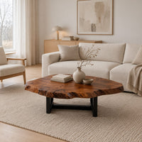 Live edge coffee table with a wide irregular slab top on a dark frame in a Scandinavian living room with white walls