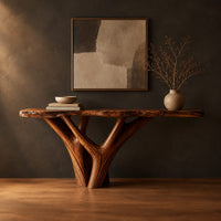 Console table with a live edge slab top on a branching trunk base in a dark studio against a charcoal plaster wall