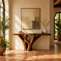 Console table with a live edge slab top on a branching trunk base in a bright entryway with arched windows and plants