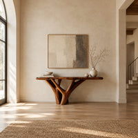 Console table with a live edge slab top on a branching trunk base in a bright open plan entryway