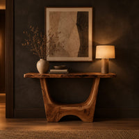 Live edge console table with a u shaped base and a low arched foot in a dark entryway at golden hour