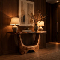 Live edge console table with a u shaped base and a low arched foot in an evening entryway with walnut wall paneling