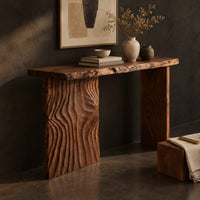 Corner detail of live edge console table with a carved ripple slab leg beside wood, brass and linen samples
