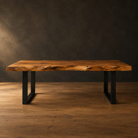 Live edge wooden desk with a thick slab top and black u shaped legs in a dark studio against a charcoal plaster wall