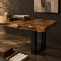 Corner detail of live edge wooden desk with a thick slab top and black u shaped legs beside wood, brass and linen samples