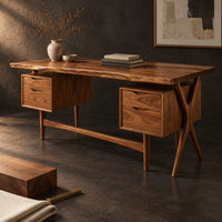 Corner detail of live edge wooden desk with four drawers and slim tapered legs beside wood, brass and linen samples