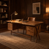 Live edge wooden desk with four drawers and slim tapered legs in an evening home office with walnut wall paneling