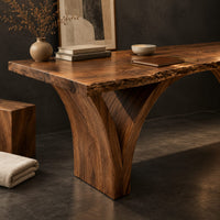 Corner detail of live edge desk on two arched slab legs that flare toward the top beside wood, brass and linen samples