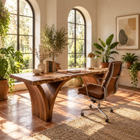 Live edge desk on two arched slab legs that flare toward the top in a bright home office with arched windows and plants