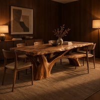 Live edge dining table on a branching tree trunk base in an evening dining room with walnut wall paneling