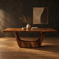 Live edge dining table on two sculpted arch pedestals in a dark studio against a charcoal plaster wall