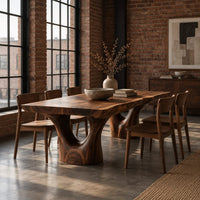 Live edge dining table on two forked trunk pedestals in an industrial loft dining room with exposed brick