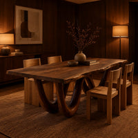 Live edge dining table on two looping wave legs in an evening dining room with walnut wall paneling