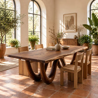 Live edge dining table on two looping wave legs in a bright dining room with arched windows and plants