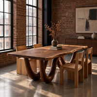 Live edge dining table on two looping wave legs in an industrial loft dining room with exposed brick