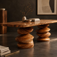 Corner detail of live edge dining table with two stacked pebble shaped pedestal legs beside wood, brass and linen samples