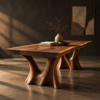 Live edge dining table on two sculpted trunk pedestals, three-quarter view showing the grain