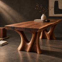Corner detail of live edge dining table on two sculpted trunk pedestals beside wood, brass and linen samples