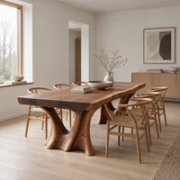 Live edge dining table on two sculpted trunk pedestals in a Scandinavian dining room with white walls