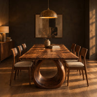 Live edge dining table on a large open ring pedestal base in a dark dining room at golden hour
