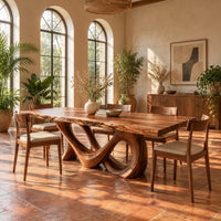 Live edge dining table with a looping figure eight base in a bright dining room with arched windows and plants