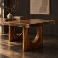 Corner detail of live edge dining table with a slab top and arch cutout legs beside wood, brass and linen samples