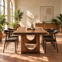 Live edge dining table with a slab top and arch cutout legs in a bright dining room with arched windows and plants