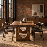 Live edge dining table with a slab top and arch cutout legs in an industrial loft dining room with exposed brick