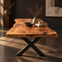 Corner detail of live edge dining table with a black x shaped base beside wood, brass and linen samples