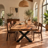 Live edge dining table with a black x shaped base in a bright dining room with arched windows and plants