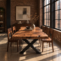 Live edge dining table with a black x shaped base in an industrial loft dining room with exposed brick