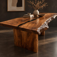 Corner detail of live edge dining table with a dark center seam and a slab base beside wood, brass and linen samples