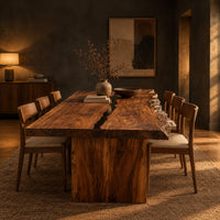 Live edge dining table with a dark center seam and a slab base in a dark dining room at golden hour