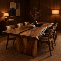 Live edge dining table with a dark center seam and a slab base in an evening dining room with walnut wall paneling