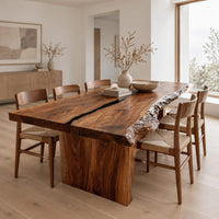 Live edge dining table with a dark center seam and a slab base in a Scandinavian dining room with white walls
