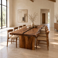 Live edge dining table with a dark center seam and a slab base in a bright open plan dining room