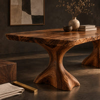 Corner detail of live edge dining table with a figured top on two flared root pedestals beside wood, brass and linen samples