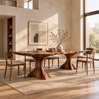 Live edge dining table with a figured top on two flared root pedestals in a bright open plan dining room
