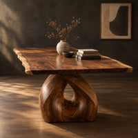 Live edge dining table on a single sculpted pedestal with a teardrop opening, three-quarter view showing the grain