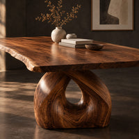 Corner detail of live edge dining table on a single sculpted pedestal with a teardrop opening beside wood, brass and linen samples