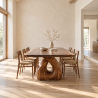 Live edge dining table on a single sculpted pedestal with a teardrop opening in a bright open plan dining room