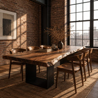 Live edge slab dining table on two open rectangular block legs in an industrial loft dining room with exposed brick